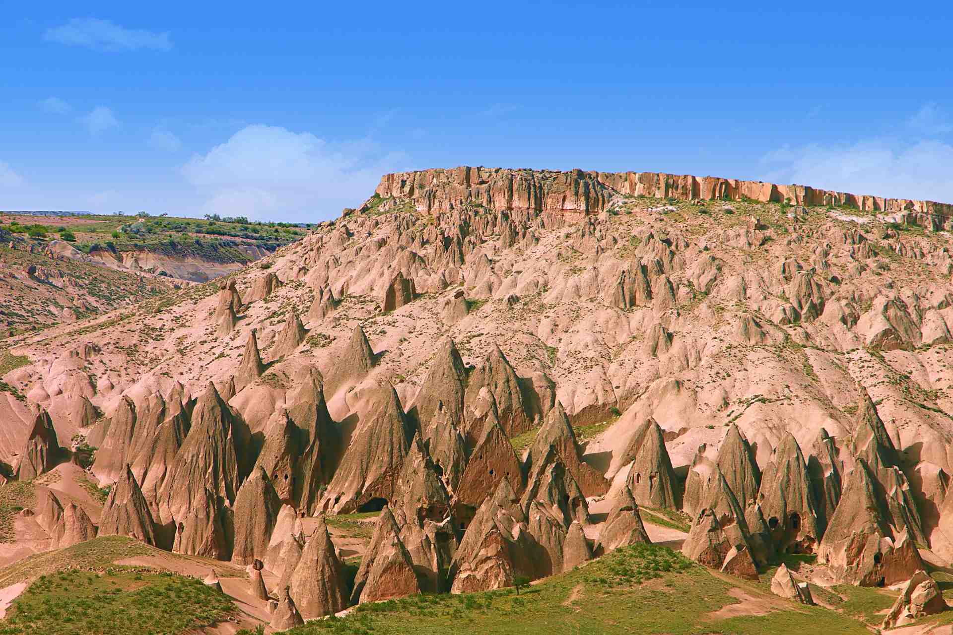 Skaliste wzgórze Kapadocji z unikalnymi formacjami skalnymi na tle błękitnego nieba
